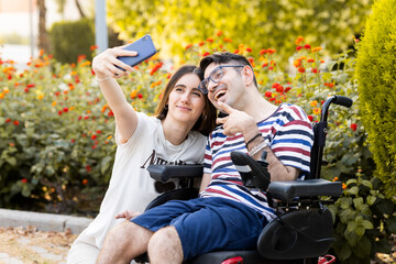 A man between the ages of 30 and 40 with a disability sits in an automatic wheelchair outdoors with...