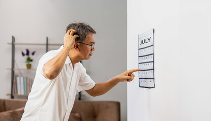 Confused Asian Senior Man With Dementia Looking at Wall Calendar