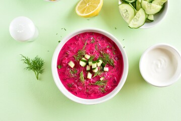 Cold summer beetroot soup in bowl over green background