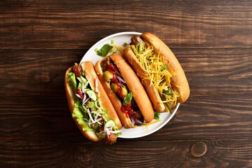 Hot dogs loaded with assorted toppings on wooden background