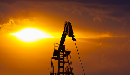 Oil beam pump or Donkey pump dramatic sunset sky - Oil pumps. Oil industry equipment