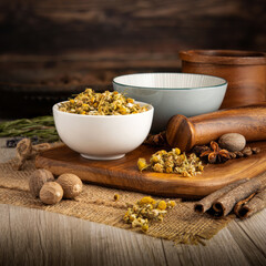 CAMOMILE FLOWERS DRIED on wooden table background. Herbs, spices and dried food baking ingredient. Mortar and different spices. Cottage kitchen. Product Photography