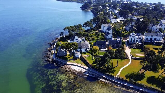 Vue a&eacute;rienne d'un quartier r&eacute;sidentiel c&ocirc;tier avec des maisons entour&eacute;es d'arbres pr&egrave;s de la mer.