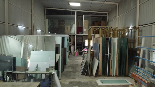 Bangalore, India 9th June 2024: Drone shots of Interior of a large glass and mirror cutting factory. Indian labor manually carries the glass in the glass factory. Glass cutting.