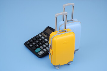 Black calculator with suitcases on blue background. Travel budget and tour price concept.