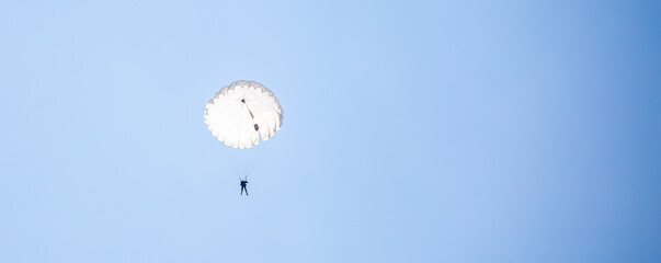 Skydiving. Flying parachutists against the background of the blue sky and mountains. Extreme sport and entertainment.