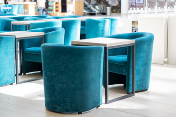 A series of blue chairs and tables arranged in a room