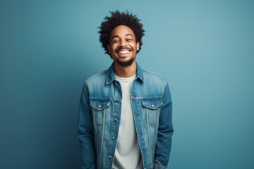 Fototapeta premium Portrait of a happy afro-american man in his 20s wearing a rugged jean vest while standing against blank studio backdrop