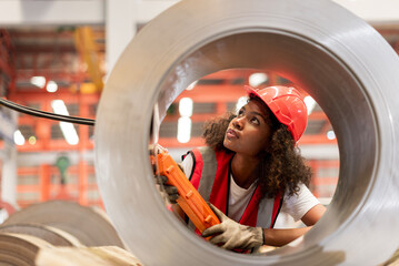 African female worker working with remote control's operating crane or lifting beam in factory