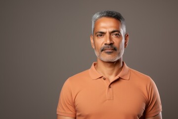 Obraz premium Portrait of a merry indian man in his 40s wearing a sporty polo shirt while standing against light wood minimalistic setup