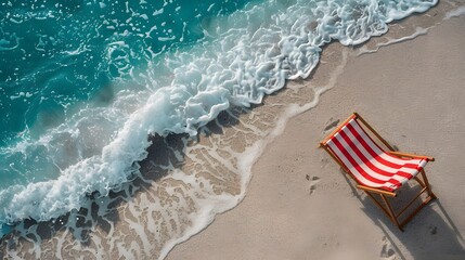 Obraz premium Aerial view of a striped beach chair on a sandy shore with turquoise waves gently crashing. Ideal summer vacation scene highlighting relaxation.