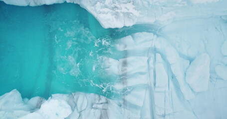 Aerial view frozen blue ice lake. Melting icy glacier cave. Snow covered formation in Antarctica washed by ocean waves. Melting iceberg polar nature environment. Global warming and climate change. - Powered by Adobe
