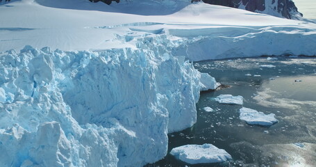 Giant snow covered glacier close up drone flight. Blue iceberg floating frozen polar ocean in sunny...