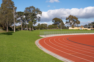 A running track with a synthetic material in a large public urban park with outdoor green space. Public recreational infrastructure and sports facility in the suburb of Reservoir, Melbourne, Australia