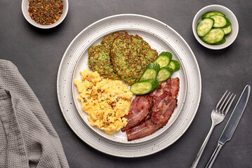 Food photography of breakfast; scrambled egg; fried; crispy; bacon, zucchini,  courgette pancake, cucumber; seasoning, brunch