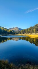 Obraz premium Tranquil Mountain Pond with Mirrored Reflection of Autumn Foliage and Azure Sky