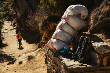 Sherpa loaded carry bag versus light Everest base camp trekkers backpack on side of EBC trek road