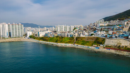 aerial view of Huinnyeoul Culture Village in Busan, Korea. The picture showcases a coastal village with a terraced landscape, colorful buildings, and a beautiful seafront.
