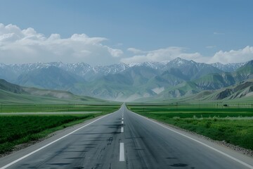 Naklejka premium A wide road leads into the distance, with green fields on both sides and snow-capped mountains in the background. The blue sky is clear, and white clouds float across it