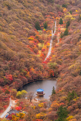 aerial view of Naejangsan National Park in Korea, showcasing vibrant autumn foliage, a serene lake, and traditional architecture amidst a mountainous landscape.