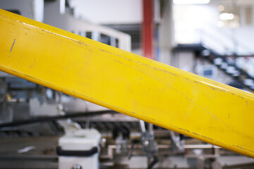 A Galvanised yellow metal bar barrier on industrial machinery metal texture background, showing signs of scratches, usage. Beautiful industrial arty textured background. Yellow painted metal.