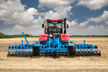 Obraz premium Rear view of a large tractor with a plow standing in a field.