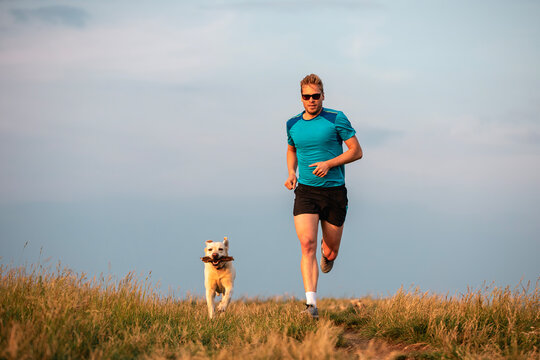 Sport lifestyle with dog. Front view of athletic man running with labrador retriever together..