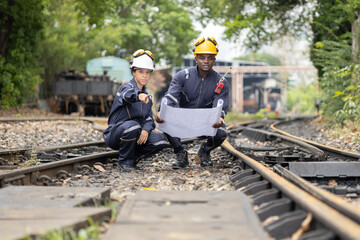 Railway Workers Discussing Plans on Railroad Track