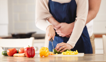 Happy couple, cooking and hug with embrace in kitchen at home for dinner, plans and family. Married people, preparing and food or salad for healthy, eating or nutrition in house in chopping peppers