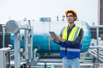 Engineer checks valves, water tanks, pumps and equipment related to hot water production pipe systems.