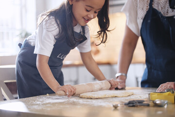 Mother, child and rolling pin in kitchen for baking with helping and teaching cookie recipe in home. Mom, girl and making biscuit dough together for learning and relationship bonding with support