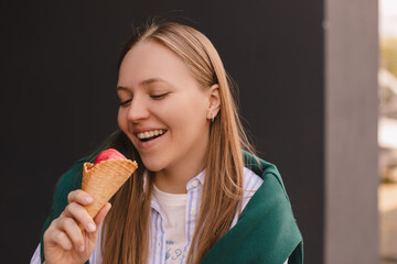 Joyful adorable teenage girl with blonde hair hold tasty ice cream smiles broadly has fun enjoys in stylish clothes isolated on black wall. Happy wow girl with gelato.