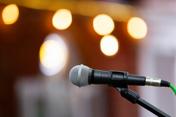 Close-up of microphone on stand against warm bokeh lighting 