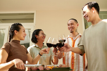 Group of friends toasting with wine glasses at barbeque party