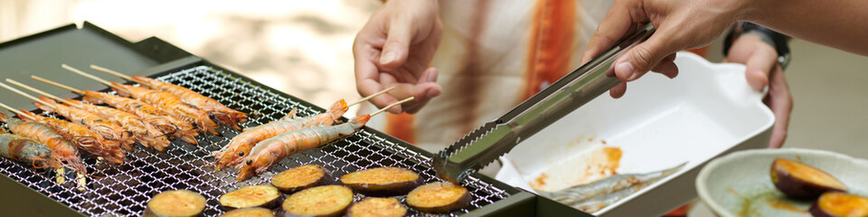 Header with people grilling eggplant and shrimps on grill