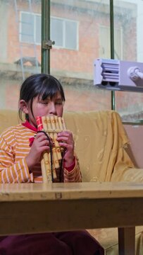 latin girl learning to play the panpipes through online classes with her cell phone - education concept