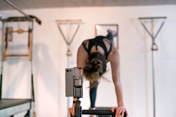Obraz premium Fit woman teaching classic pilates exercises from her cell phone.