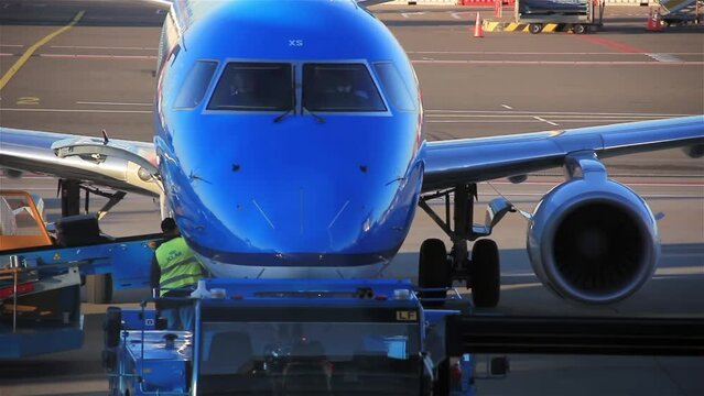 Ground Crew Unloading Luggage from A Passenger Aircraft at Amsterdam Schiphol International Airport.