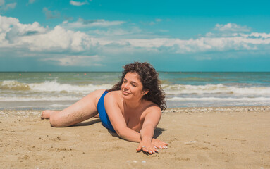 Hispanic middle age woman with a curly hair relaxing on a beach. Natural women's beauty, feminine concept
