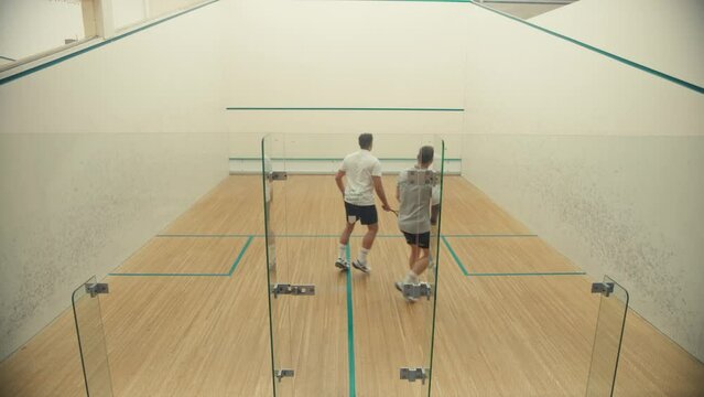 Two guys playing squash at the court