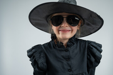 Portrait of a little Caucasian girl in a witch costume on a white background. 