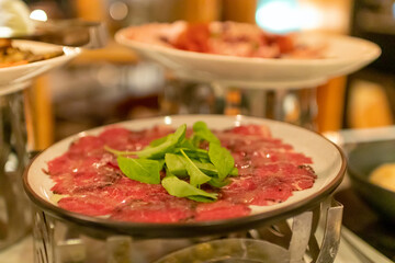 Close-up of a plate of thinly sliced rare roast beef with watercress garnish on top.