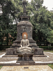 Fototapeta premium a Buddha sitting cross-legged on a lotus-shaped stone carving, complete with a stupa behind him 