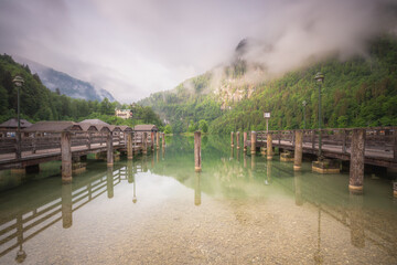 Tranquil lakeside dock with misty green mountains, peaceful and relaxation