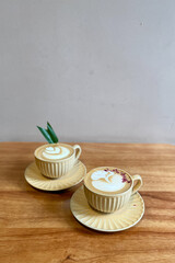 Beautiful latte decorated with dry rose petals and pandan leave on the wood table in the cafe.