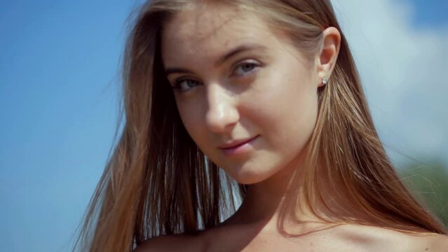 young woman in a bikini walks on the sunny beach. A girl with elastic buttocks is sunbathing on the beach. The charming thin model poses to the camera. Woman in bikini relaxing on sandy beach. Beauty 