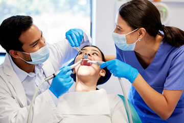Dentist, team and patient in clinic with equipment for consultation, oral hygiene or medical procedure. Service, doctor man and nurse woman with client for teeth extraction, cleaning or dental care