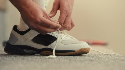 Squash player tying his shoe