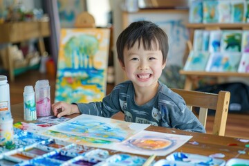 Fototapeta premium Happy little Asian child intently painting watercolor art on table develop learning Train small muscles