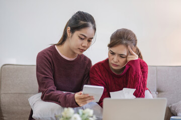 Two women focused on calculating finances with laptop at home. Concept of financial planning, collaboration, and budgeting